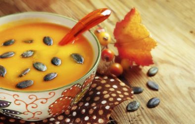 Autumn pumpkin soup with seeps on a wood table
